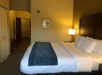 A hotel room with a kin bed, side table and lamp, and a small painting on the wall at the Comfort Inn & Suites Ukiah Mendocino County.