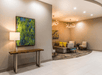 The lobby of the Comfort Inn & Suites Valdosta with a buffet table with green art over it and a sitting area with couches and chairs in the background.