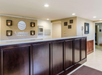 Hotel reception desk at Comfort Inn & Suites with a logo on the wall, dark wood paneling, and a light-colored countertop.