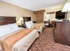 A hotel room with two queen size beds with a large dress and a small table at the Comfort Inn at Thousand Hills in Branson, Missouri.