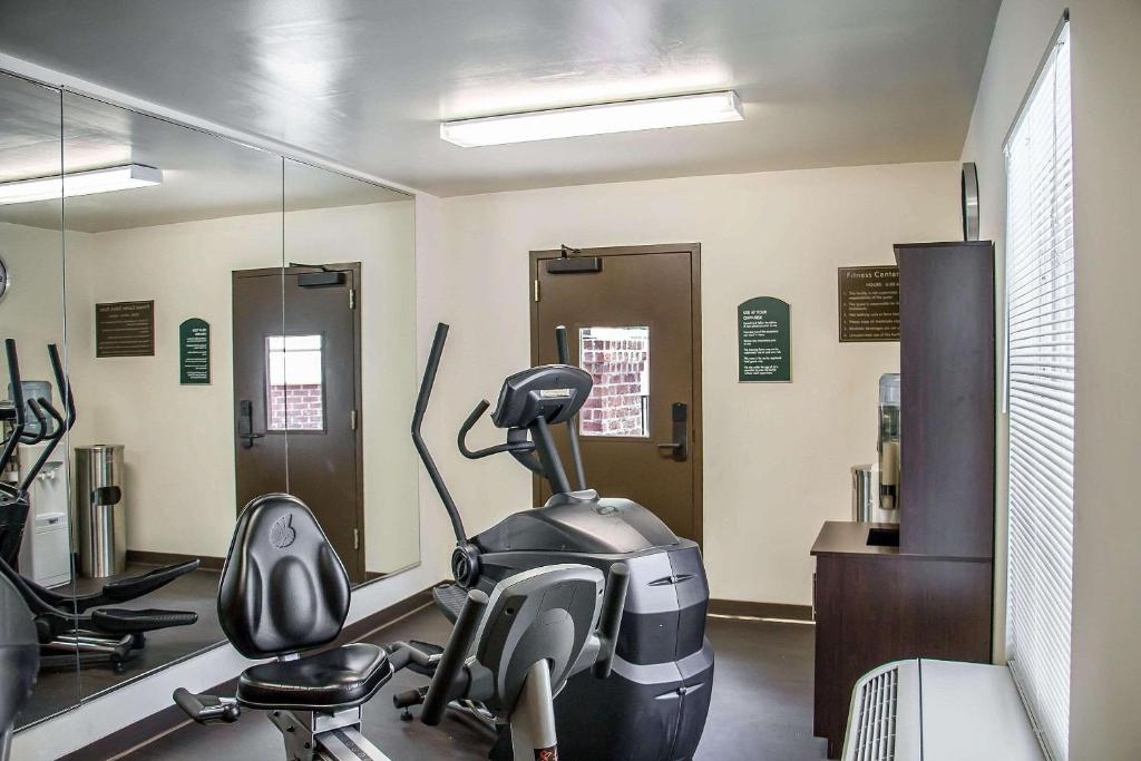 Small gym room with an exercise bike, a mirrored wall, and a storage unit. A window and two doors are visible.