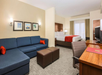One king bed, seating area with sofa bed, work desk and flat-screen TV inside a guest room.