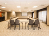 Meeting facility with white projector screen and U-type seating setup.