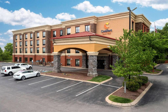 Outdoor parking and entrance to the hotel with the hotel sign.