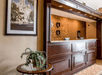 The dark wooden front desk at the Comfort Suites New Braunfels with a stone wall behind it and a house plant on a table next to it.