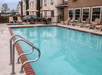 An outdoor swimming pool with light blue water and chairs lining the sides on a sunny day at the Comfort Suites New Braunfels.