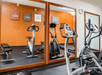 A fitness center with a treadmill, elliptical, and stationary bike in front of a wall of mirrors at the Comfort Suites New Braunfels.