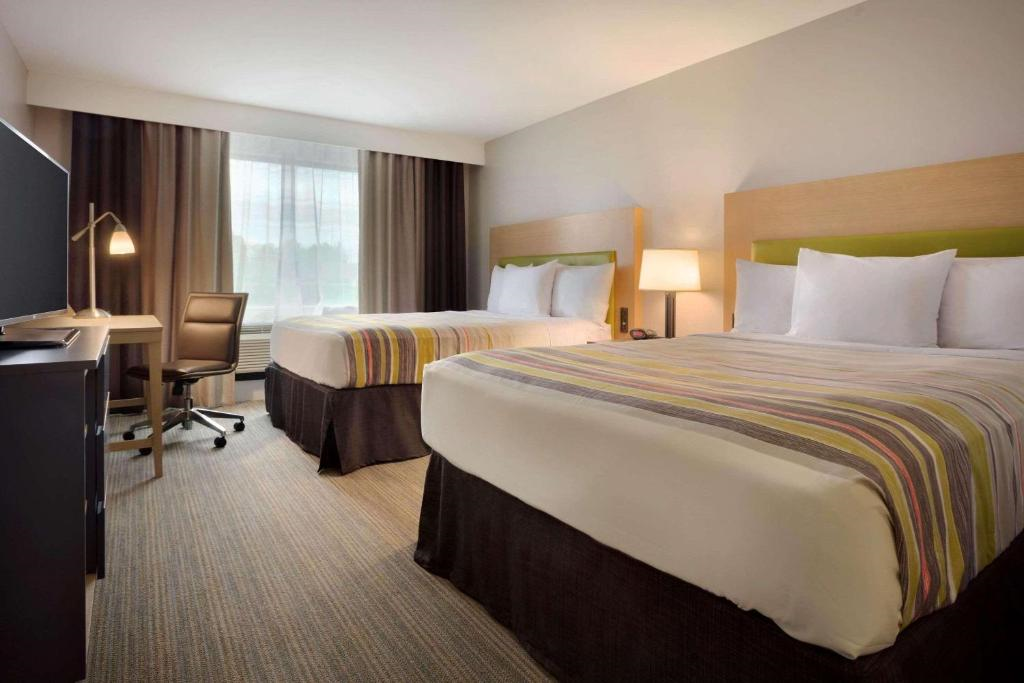 Room with two queen beds, a work desk, and a TV