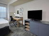 Flat-screen TV, work area, and a bed