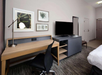 Flat-screen TV, work area, and a bed inside a guest room