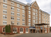 The beige front exterior of the Country Inn & Suites by Radisson with clouds in the sky over in near Minneapolis, Minnesota.