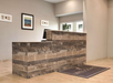 Front desk with a wooden counter, framed art, and a welcome mat