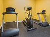 Small gym room with two treadmills and an elliptical machine against a yellow wall.
