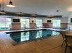 Indoor swimming pool area with chairs and large windows. Safety signs are visible on the walls.