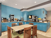 A breakfast area with blue walls and cabinets and an assortment of food options with a table and chairs in front of it.