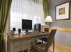 A small desk with a desk top computer, printer, lamp, and chair in front of a large window at the Country Inn & Suites.