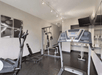 A small fitness center with a few different work out machines, a large mirror, and a television mounted in the corner.