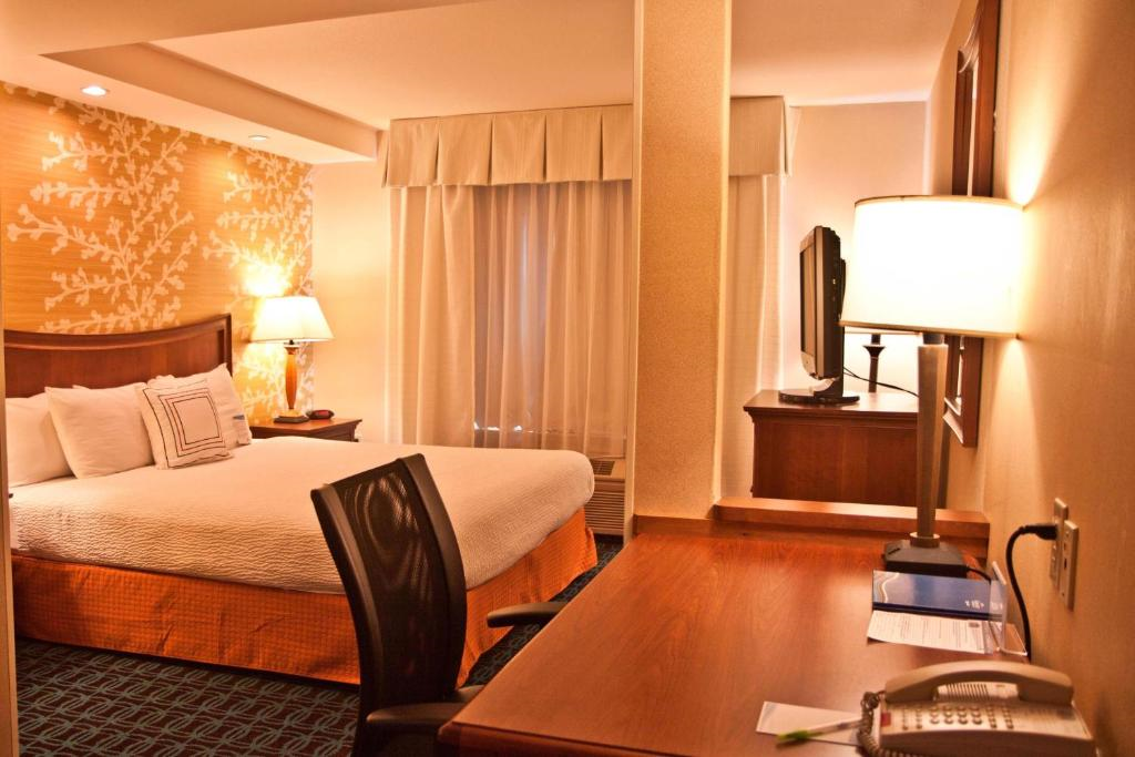 Guest room with one king bed, work desk with lamp, and TV.