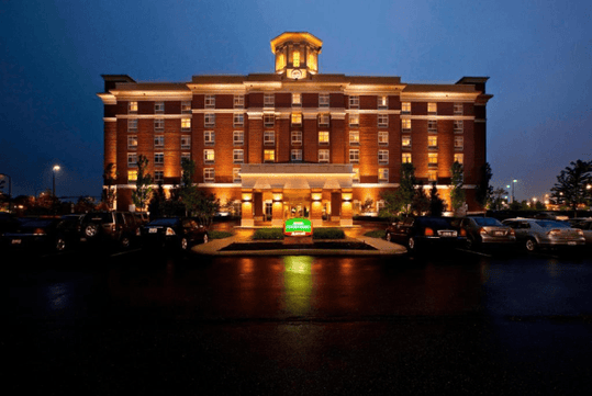 Wide shot of the Courtyard Columbus Easton at night with the hotel light illuminating it and several cars in the parking lot.