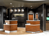 Two small geometric front desks with a dark brown wall behind them and lights above them at the Courtyard Columbus Easton.