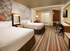 Two queen beds, telephone, lamp, armchair, work desk and a flat-screen TV inside a non-smoking room.