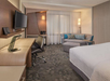 1 King bed, seating area and a work desk and chair inside a guest room.