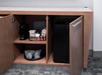 A wooden cabinet with open doors reveals a coffee maker, coffee supplies, and a mini fridge inside on a carpeted floor.