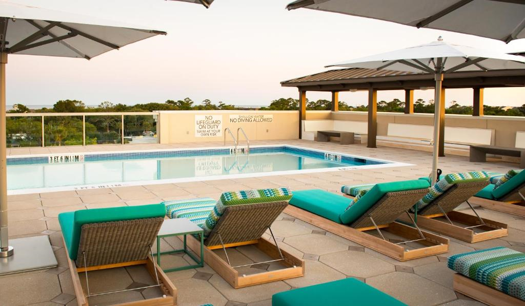 Rooftop pool with lounge chairs and umbrellas, overlooking a scenic view. Signs indicate no diving and no lifeguard on duty.