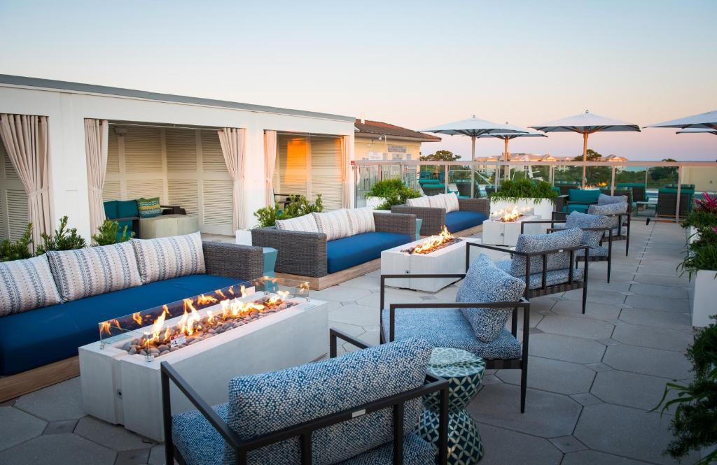 Outdoor rooftop lounge with modern seating, fire pits, and umbrellas at sunset.