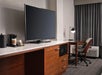 Coffee maker, flat-screen TV, and a workstation inside a guest room.