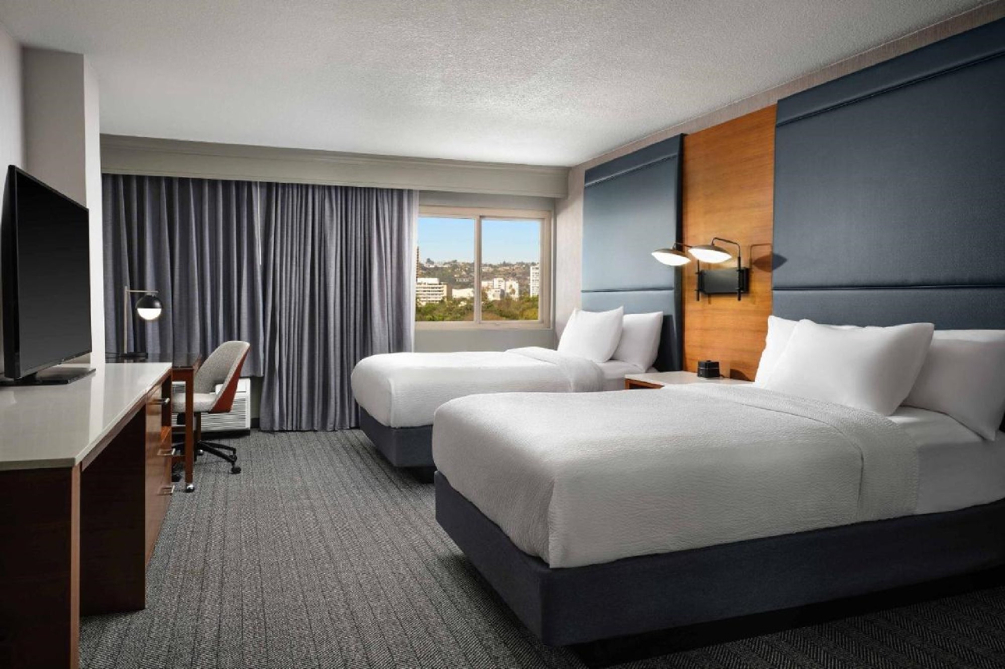 2 Double beds, flat-screen TV, and a workstation inside a guest room.