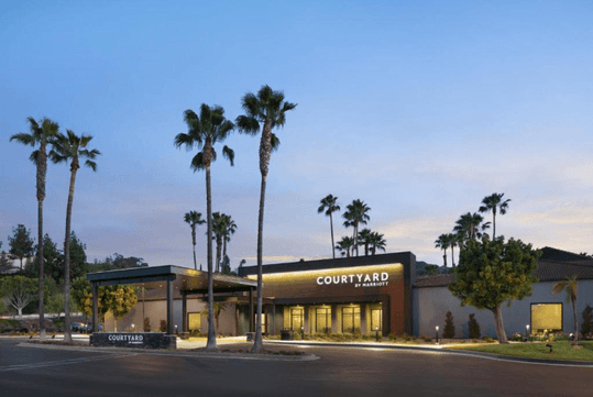Modern hotel exterior surrounded with trees.