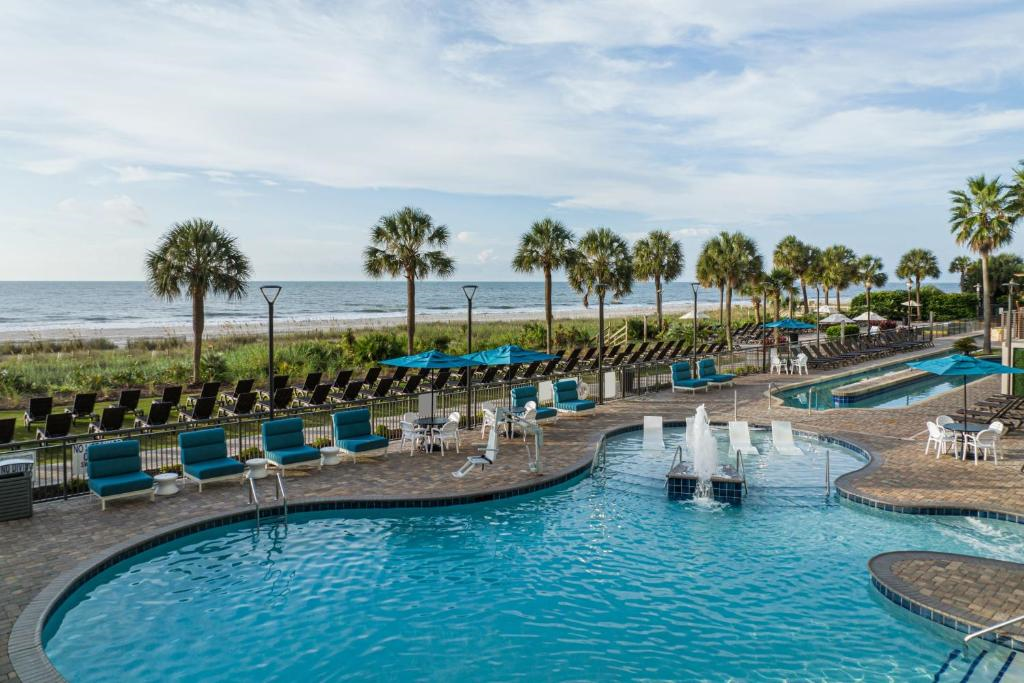 View of the oceanfront outdoor pool and lazy river, with sun loungers.