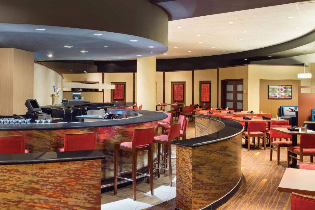 Hotel bar and lounge area with red cushioned seating, curved bar counter, and modern decor.