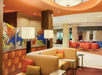 Hotel lobby with modern decor, featuring beige and orange seating, colorful abstract art, and ambient lighting.