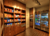A small convenience store corner featuring shelves with snacks and a refrigerated section with drinks.
