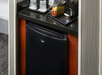 Small hotel mini-fridge with a black door, topped with a coffee maker, cups, and packets of coffee and tea on a tray.