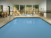 Indoor pool with surrounded by floor-to-ceiling windows and sun loungers.