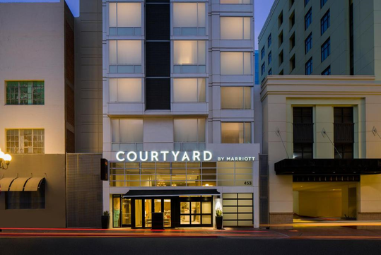 Entrance of a Courtyard by Marriott hotel, featuring illuminated signage and a modern exterior with large windows.
