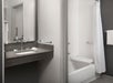 Private bathroom with vanity area and an accessible bathtub with folding shower bench and grab bars.