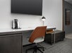 Desk and chair, coffee maker, and a wall-mounted TV inside a guest room.
