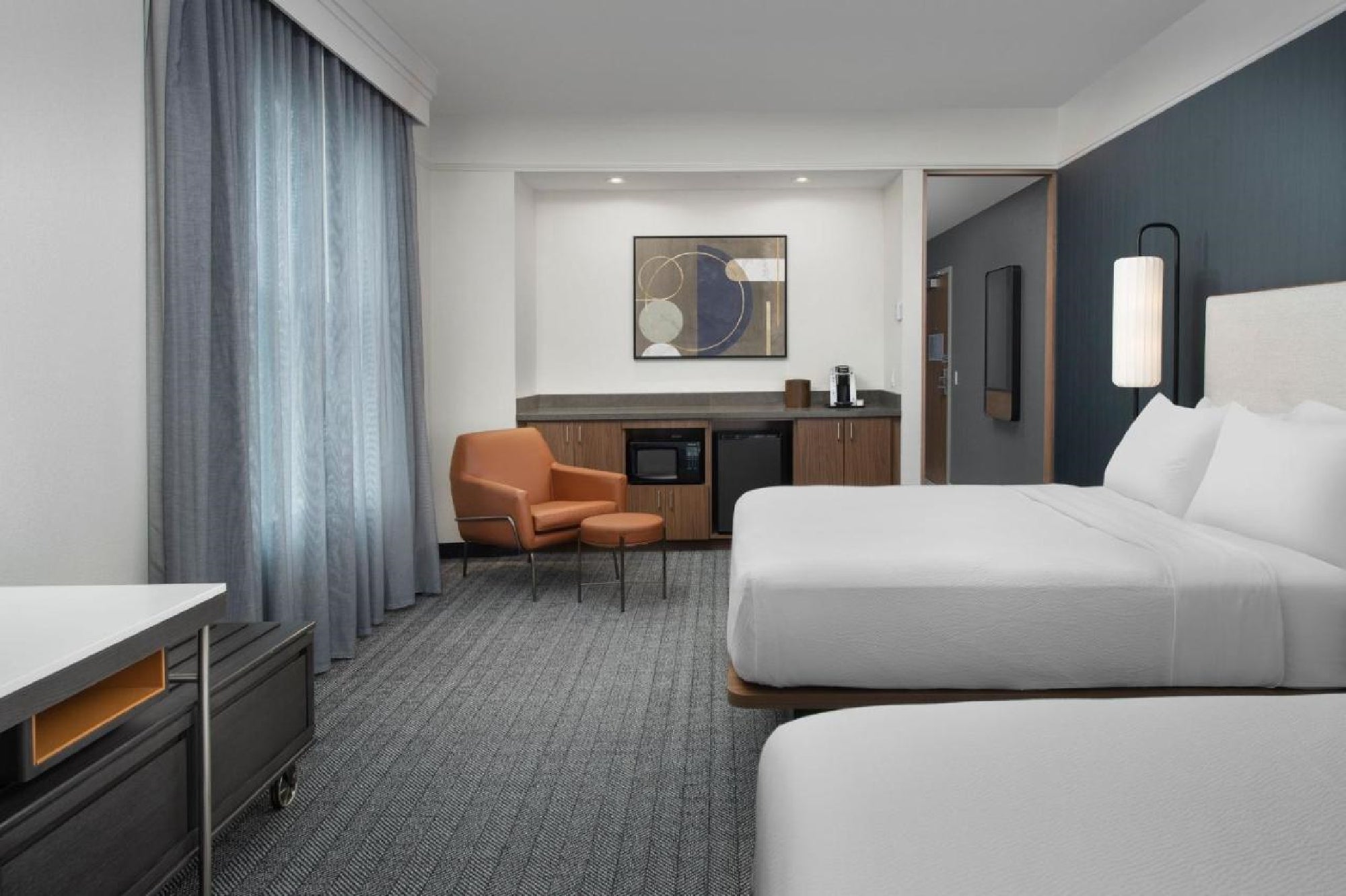 Guest room with 2 Queen beds, mini fridge, microwave, and a comfortable soft seating.