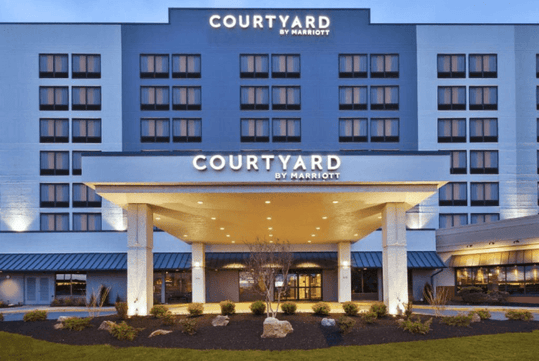 Front view of a Courtyard by Marriott hotel with a lit entrance and landscaped surroundings.