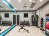 A compact gym with a bench, free weights, exercise balls, a multi-gym machine, and wall mirrors.