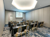 A conference room with rows of tables and chairs facing a projector screen displaying the Crowne Plaza logo.