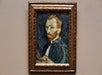 A framed portrait of a man with a red beard and blue clothing, painted with textured brush strokes, displayed on a neutral wall.