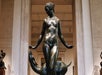 Bronze statue of a nude woman with a gazelle, displayed in an indoor museum setting.