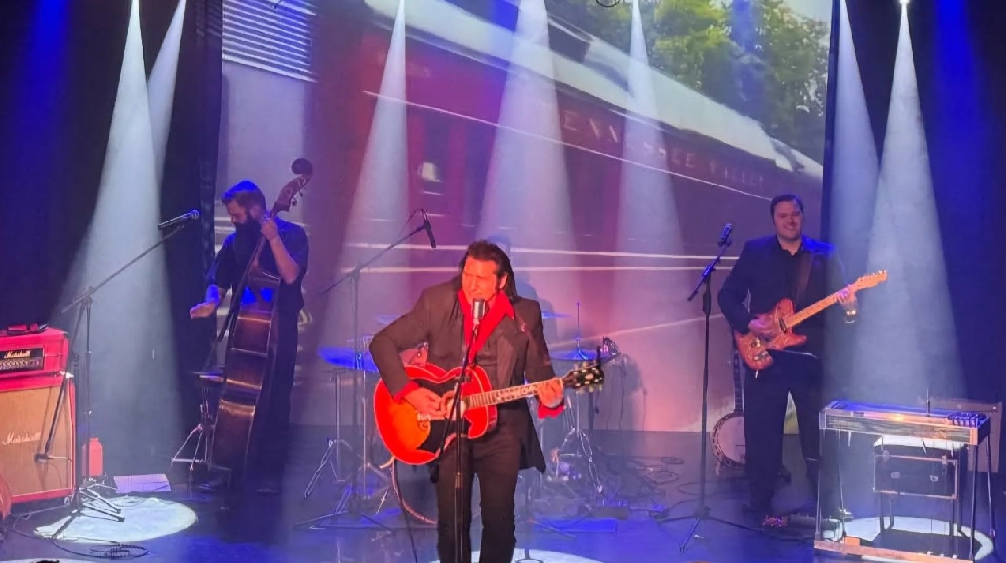 Dan Wagner with playing his guitar with the band on the stage.