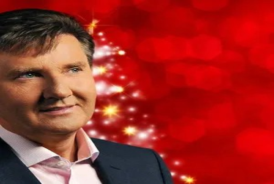 Man in a suit with a festive red background and glowing lights.
