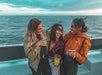 Group of friends enjoying drinks and laughing on a boat cruise.